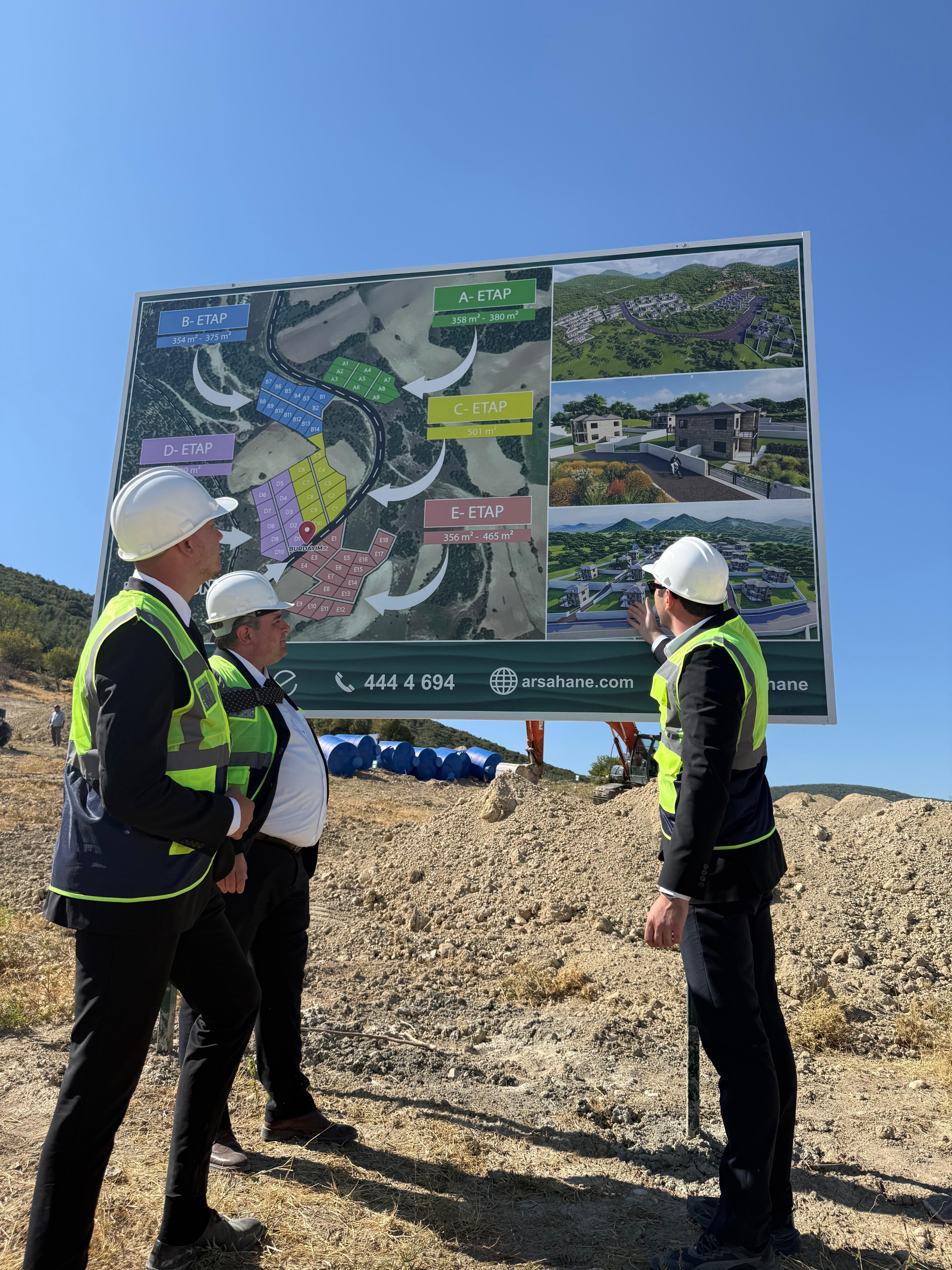 Sahada Arsahane ekibi — etap planı tanıtım panosu önünde